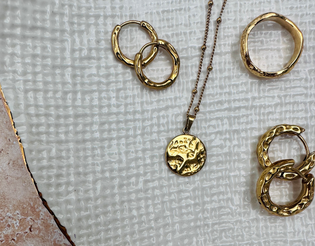 collection of gold plated waterproof jewellery on a white plate